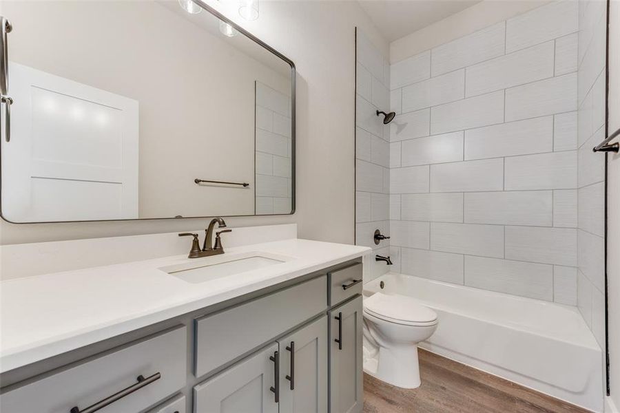 Full bathroom featuring wood-type flooring, vanity, toilet, and tiled shower / bath