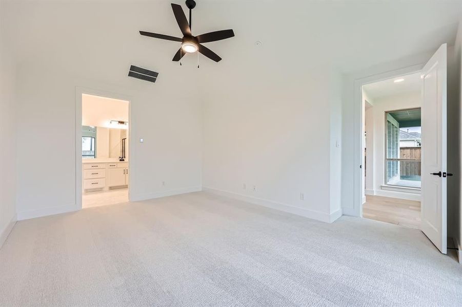 Unfurnished bedroom with ceiling fan, ensuite bath, and light carpet