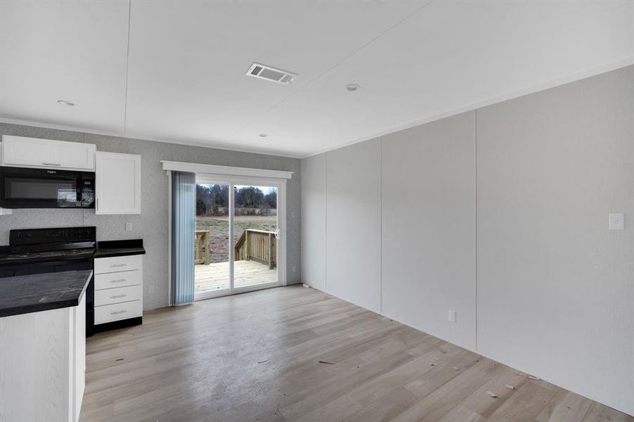 Kitchen featuring black appliances, white cabinets, light wood finished floors, and a decorative wall