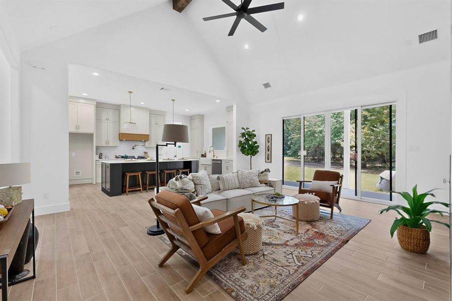 Spacious open-concept living area featuring high vaulted ceilings, recessed lighting, and wood-finish flooring