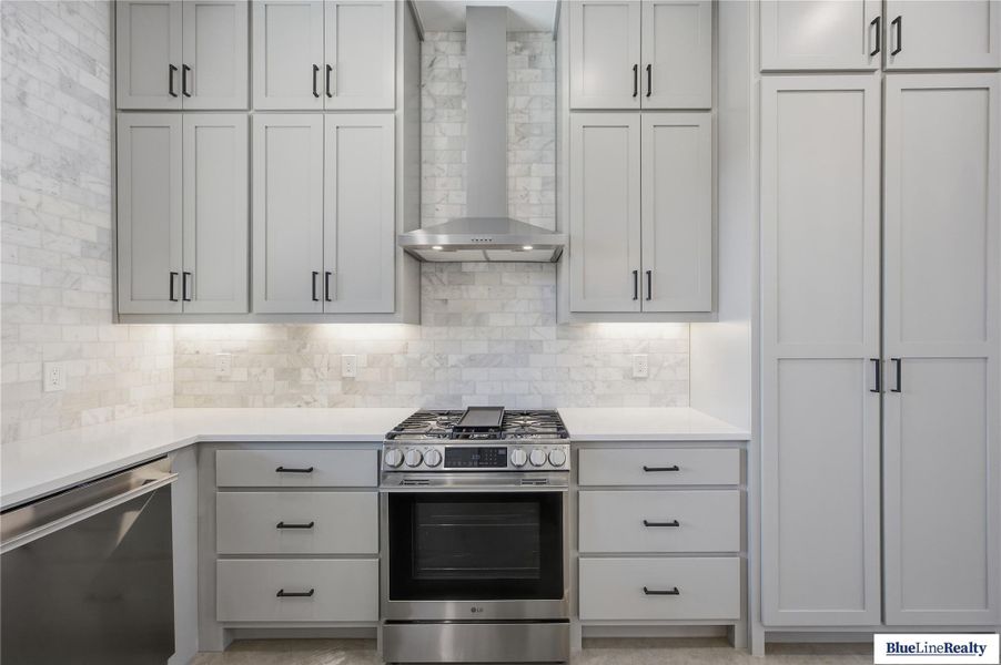 Kitchen featuring stainless steel appliances, light stone counters, and tasteful backsplash