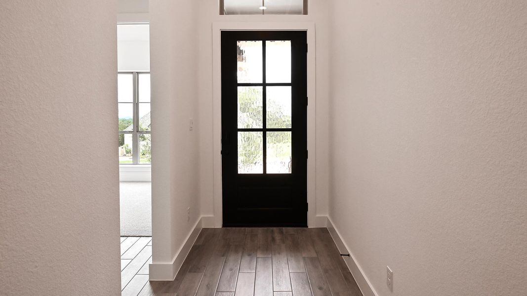 Doorway with a textured wall, wood finished floors, and baseboards Doorway with a textured wall, wood finished floors, and baseboards