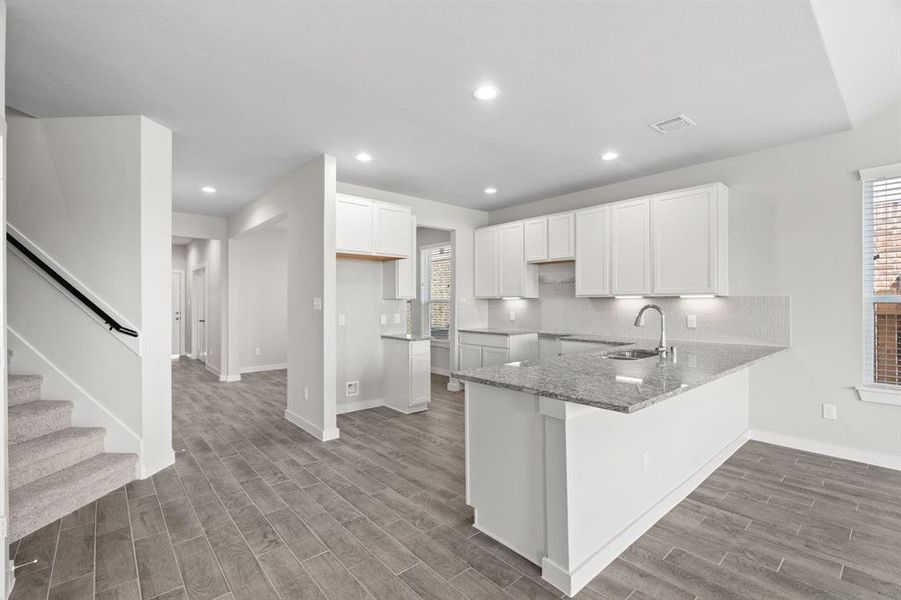 The kitchen is a culinary haven, featuring granite countertops, a tile backsplash, stainless steel appliances, 42” upper cabinets, and undercabinet lighting. Sample photo of completed home with similar floor plan. As-built interior colors and selections may vary.