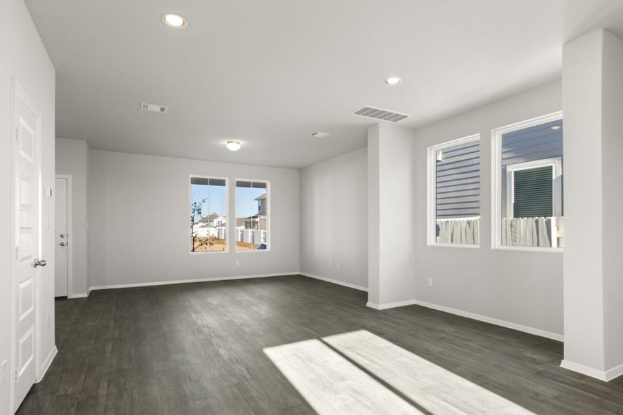 Image of a dining room with light grey walls, dark vinyl flooring, and windows