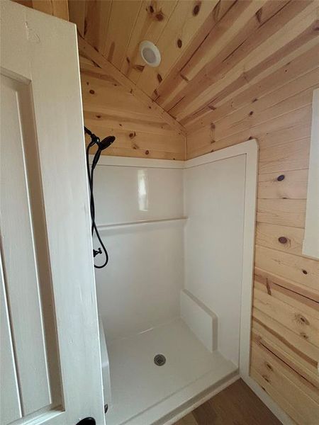 Full bath featuring lofted ceiling, wood walls, wooden ceiling, a shower, and wood finished floors Full bath featuring lofted ceiling, wood walls, wooden ceiling, a shower, and wood finished floors