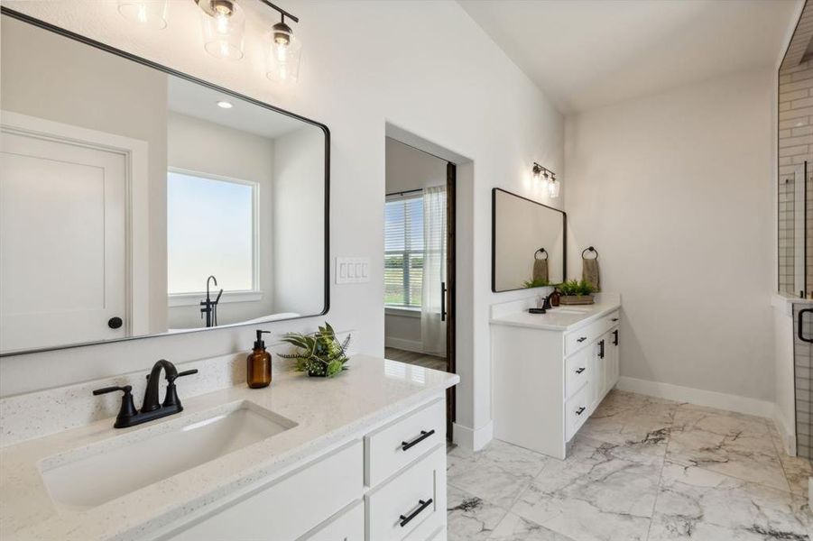 Spacious bathroom featuring dual vanities with white cabinetry and light-toned countertops