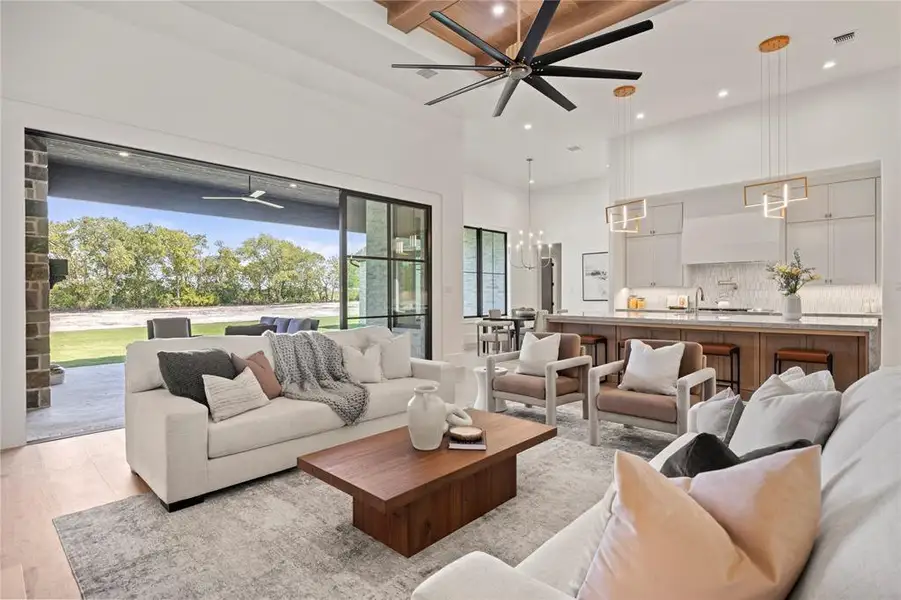 Living room featuring ceiling fan, recessed lighting, beam ceiling, a towering ceiling, and a chandelier