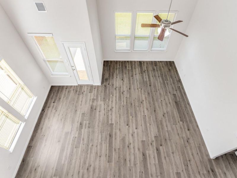 Unfurnished living room with plenty of natural light, wood finished floors, and a ceiling fan