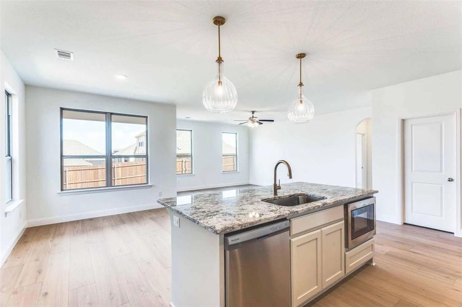 Kitchen featuring dishwasher, a sink, built in microwave, light wood-type flooring, and pendant lighting