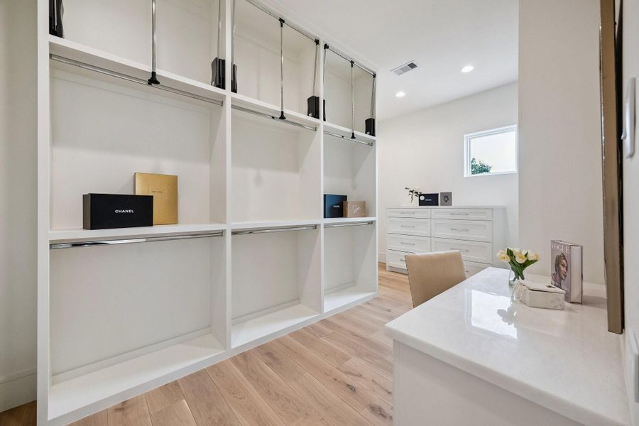 Spacious primary closet to feature built-in storage and ample room for hanging clothes with pull-down bars for accessing all custom storage solutions. **Photo is of another home in the community and for information purposes only. Buyer to verify all details.** Spacious primary closet to feature built-in storage and ample room for hanging clothes with pull-down bars for accessing all custom storage solutions. **Photo is of another home in the community and for information purposes only. Buyer to verify all details.**