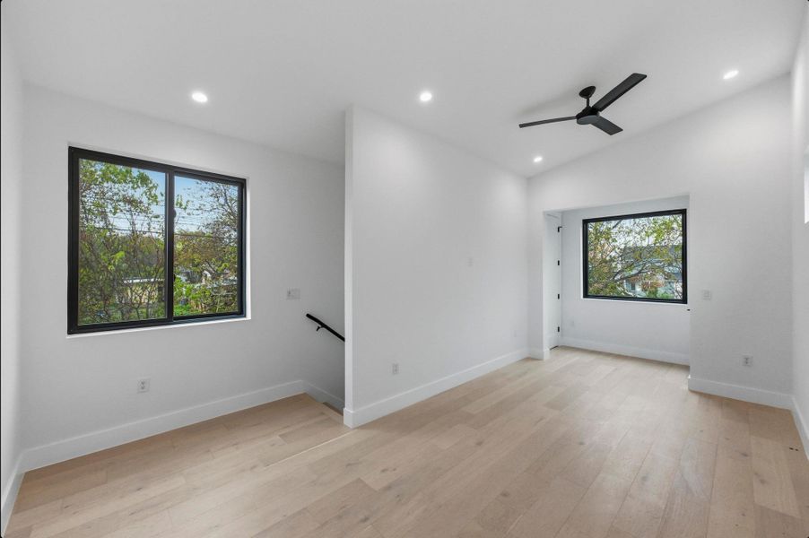 Empty room with light wood-type flooring, ceiling fan, recessed lighting, and vaulted ceiling Empty room with light wood-type flooring, ceiling fan, recessed lighting, and vaulted ceiling