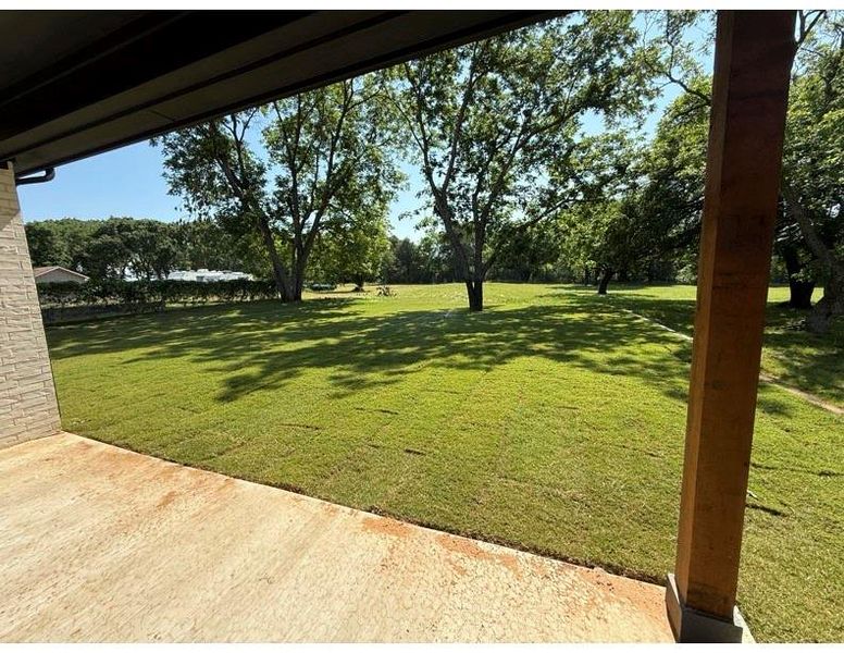Expansive outdoor patio with a concrete surface, overlooking a lush green lawn