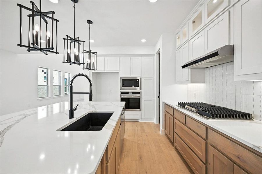 Kitchen featuring pendant lighting, light wood-style floors, white cabinetry, recessed lighting, and stainless steel appliances Kitchen featuring pendant lighting, light wood-style floors, white cabinetry, recessed lighting, and stainless steel appliances