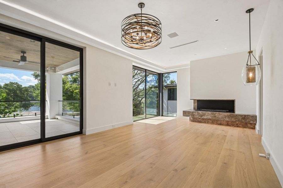Warm hardwood floors complement a modern stone fireplace and towering glass doors leading outside. Warm hardwood floors complement a modern stone fireplace and towering glass doors leading outside.