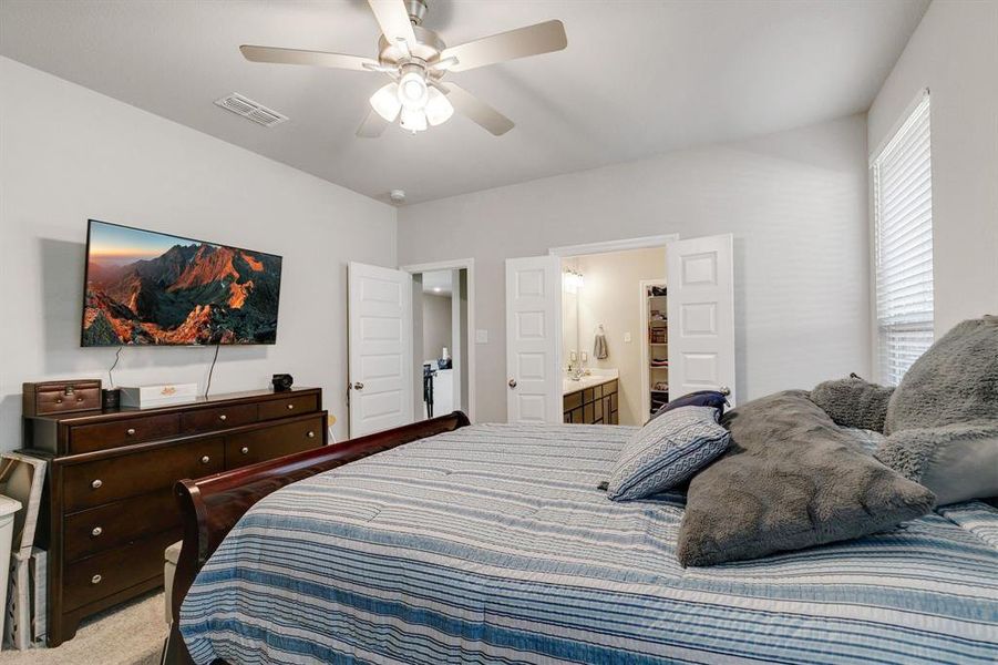 Carpeted bedroom featuring connected bathroom and ceiling fan