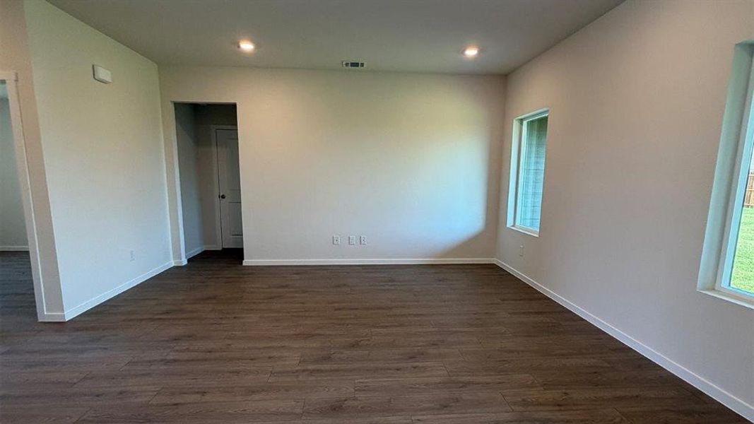 Spacious room featuring wood-finish flooring, two windows, recessed lighting, and neutral wall paint Spacious room featuring wood-finish flooring, two windows, recessed lighting, and neutral wall paint