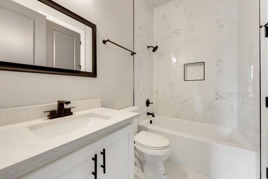 Full bathroom with toilet, vanity, and tiled shower / bath