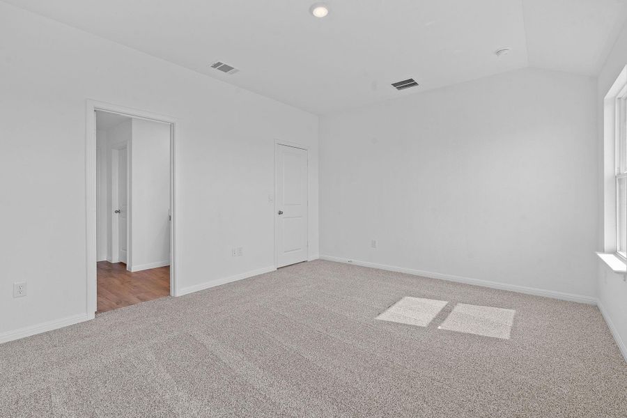 Unfurnished bedroom with light colored carpet, vaulted ceiling, and recessed lighting