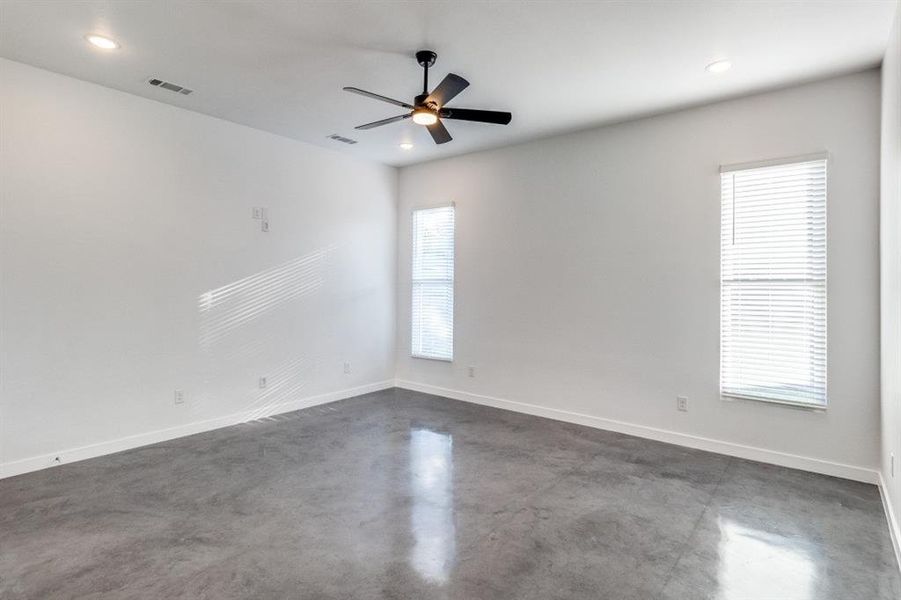 Empty room featuring a wealth of natural light, concrete floors, and ceiling fan