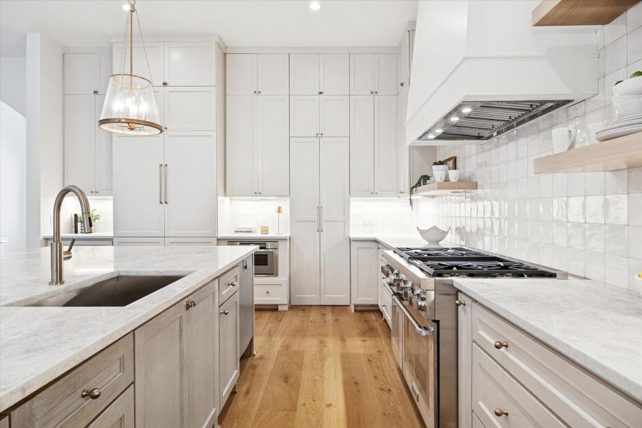 Well-appointed kitchen with Taj Mahal quartzite counters, premium appliances, ample cabinetry, and a spacious island workspace.