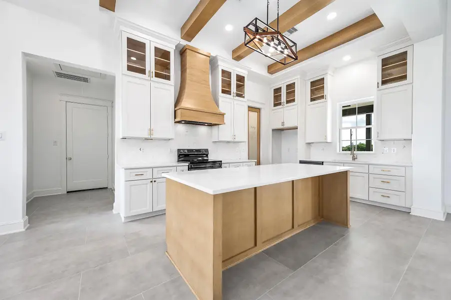 A spacious kitchen with a large center island, plenty of cabinet space, warm wood finishes, and exposed beams that bring the whole space together.