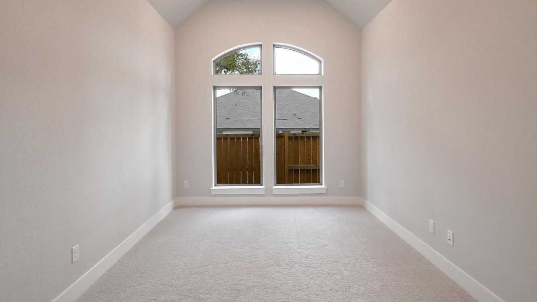 Empty room with light carpet and vaulted ceiling