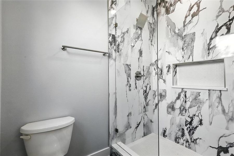 Bathroom with toilet and a marble finish shower