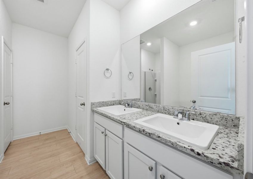 Primary bathroom featuring a double vanity with granite countertop and a large mirror. Primary bathroom featuring a double vanity with granite countertop and a large mirror.