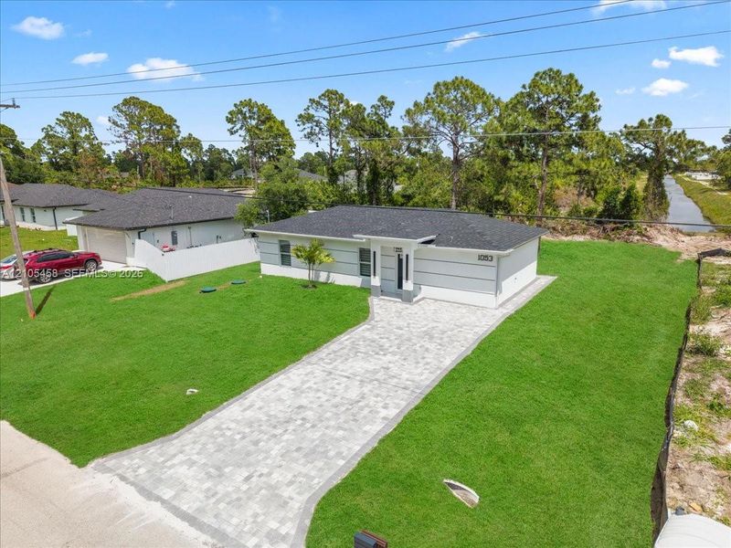 Modern exterior with light gray siding, dark roof, and a paver driveway Modern exterior with light gray siding, dark roof, and a paver driveway