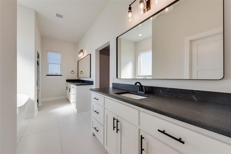 Bathroom with tile patterned floors, a washtub, and vanity