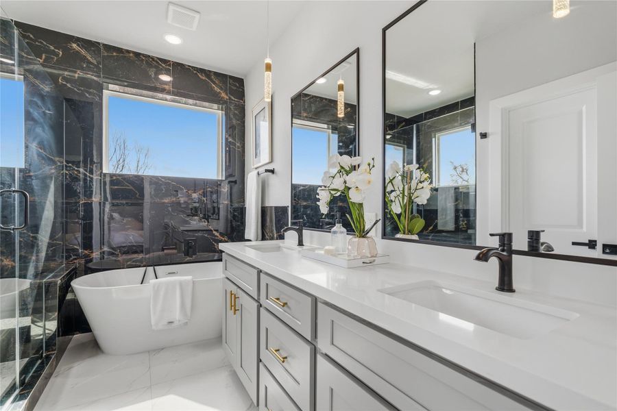 Primary bath with freestanding soaking tub and separate glass-enclosed walk-in shower.Dual vanity with quartz counters, matte black fixtures, and striking designer tile.Striking tile surround, matte black fixtures, and abundant natural light complete the space.