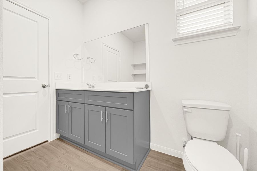 Well-lit bathroom showcasing a grey vanity cabinet and an updated mirror setup.