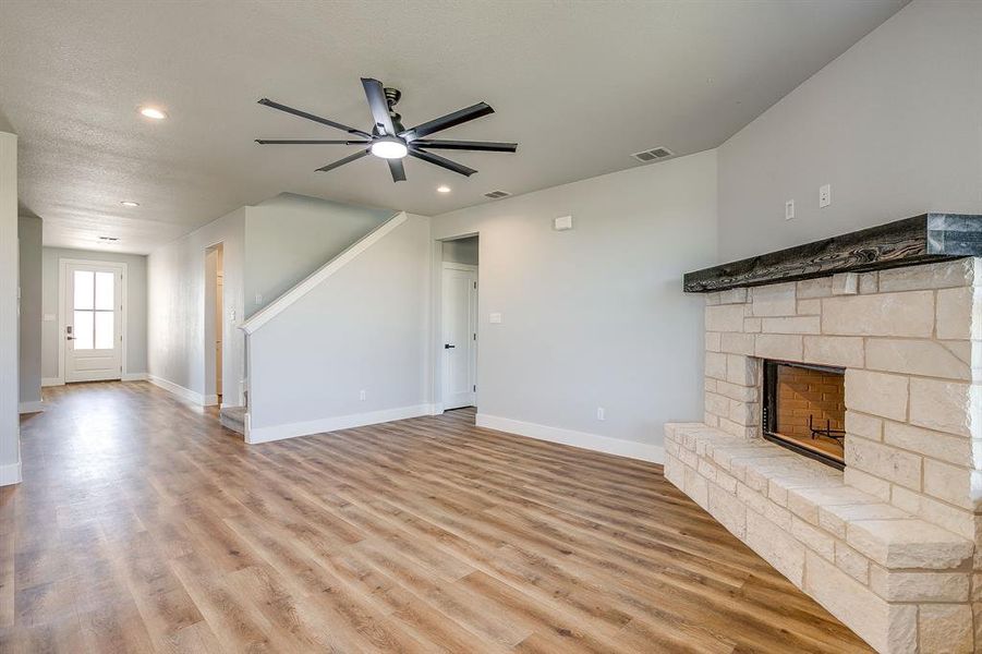 Unfurnished living room with a fireplace, light wood-style floors, a ceiling fan, and recessed lighting