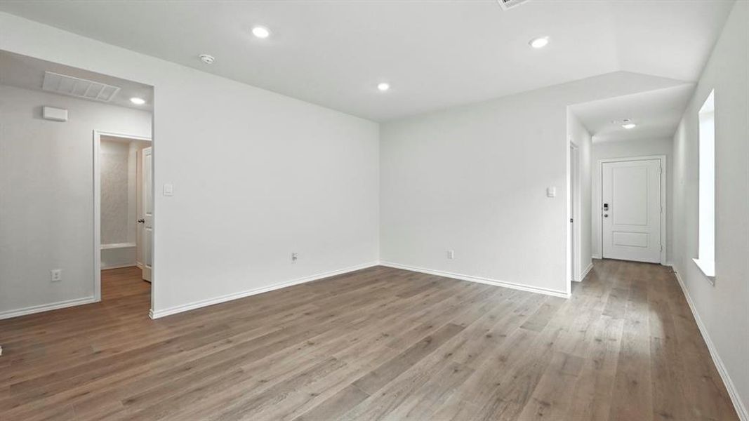 Spacious interior featuring wood-finish flooring, recessed lighting, white trim, and a paneled entry door Spacious interior featuring wood-finish flooring, recessed lighting, white trim, and a paneled entry door