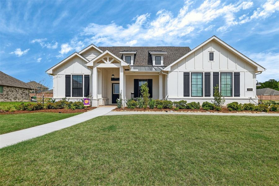 This home boasts outstanding curb appeal with plush landscaping and elegant metal roof accents, creating a welcoming and stylish exterior.