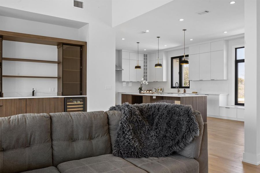Living room with light wood-type flooring, beverage cooler, and recessed lighting