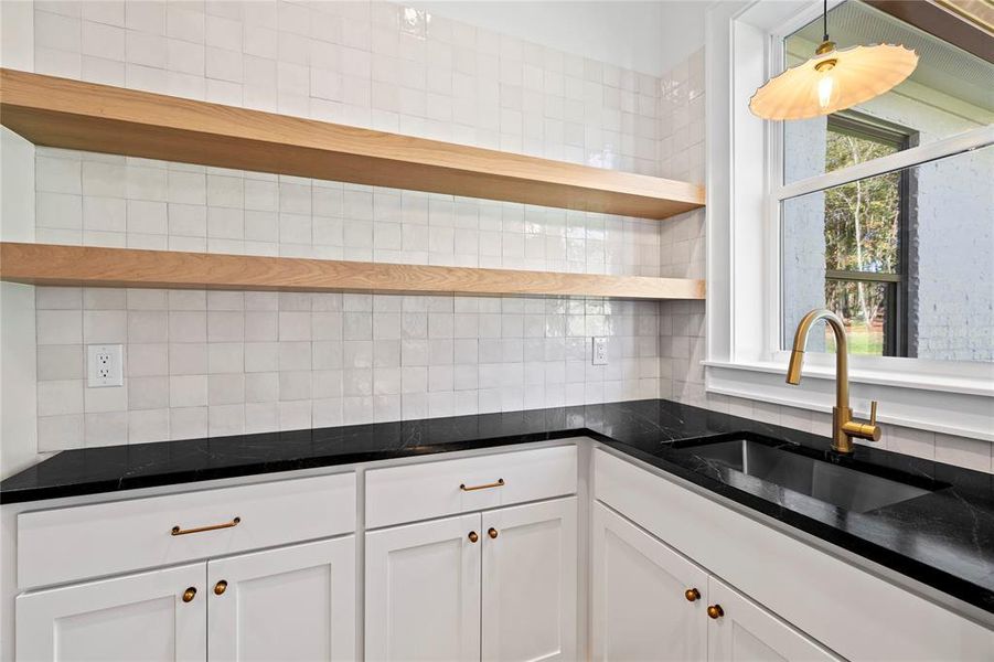 Kitchen with open shelves, white cabinets, dark stone countertops, and decorative backsplash