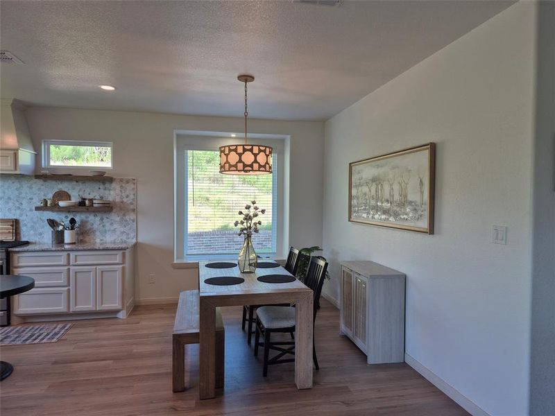 Dining space featuring light wood finished floors, a textured ceiling, and recessed lighting