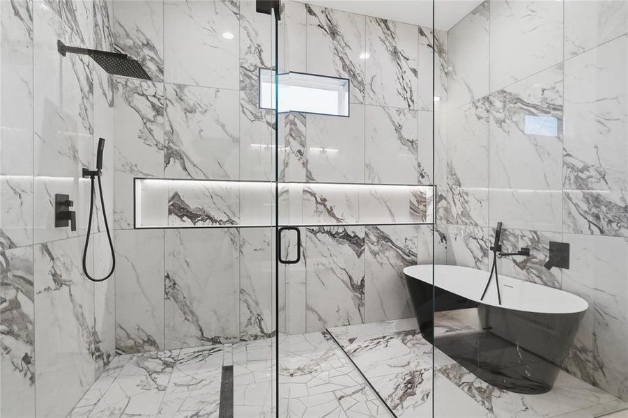 Walk-in shower with full-height white and gray veined tile, complemented by a freestanding black soaking tub Walk-in shower with full-height white and gray veined tile, complemented by a freestanding black soaking tub