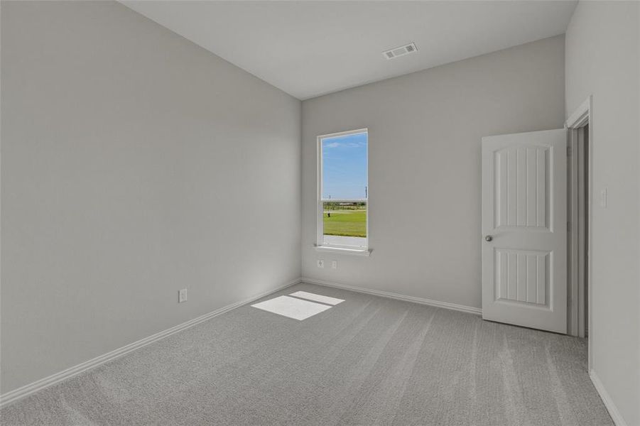 Bright interior room featuring a large window, light gray carpet, and a white paneled door Bright interior room featuring a large window, light gray carpet, and a white paneled door