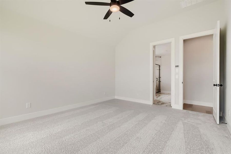 Spacious main bedroom room featuring vaulted ceilings, a contemporary ceiling fan, and light-toned carpet flooring