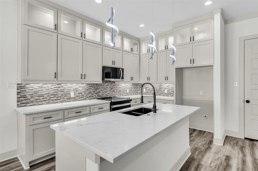 Kitchen featuring glass insert cabinets, light stone countertops, black / electric stove, a kitchen island with sink, and recessed lighting
