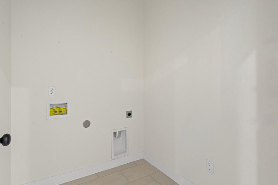 Laundry area with tile flooring and white baseboards Laundry area with tile flooring and white baseboards