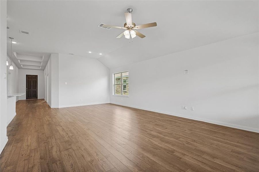 Unfurnished living room featuring vaulted ceiling, dark hardwood / wood-style flooring, and ceiling fan