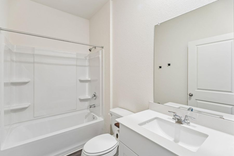 Bathroom with vanity, shower / bath combination, and a textured wall