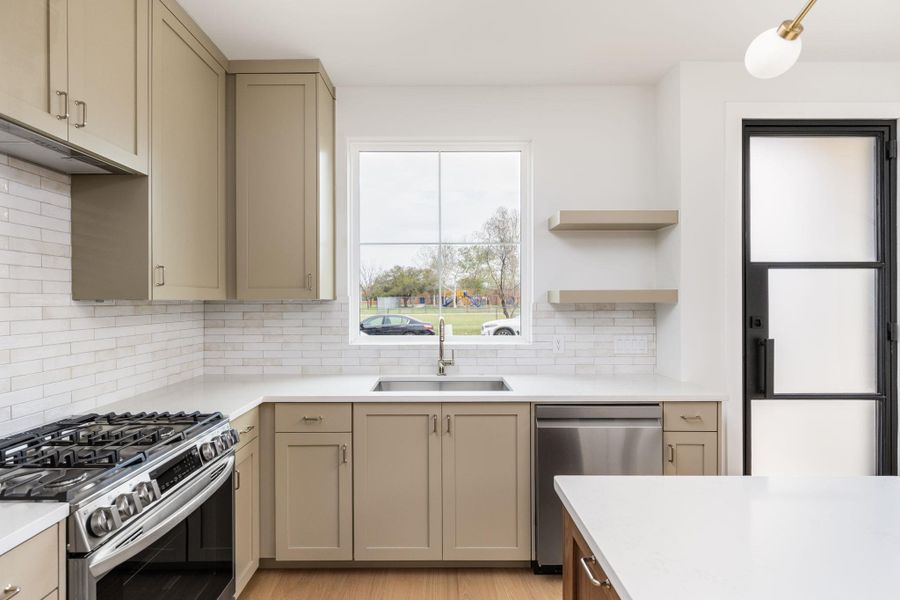Kitchen featuring stainless steel appliances, open shelves, and cream cabinets