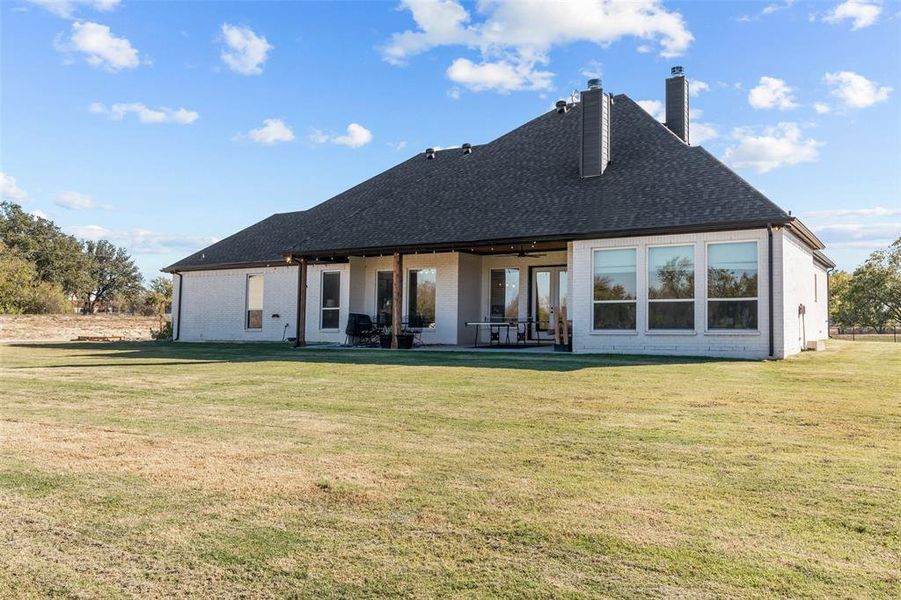 Back of property featuring a yard and a patio