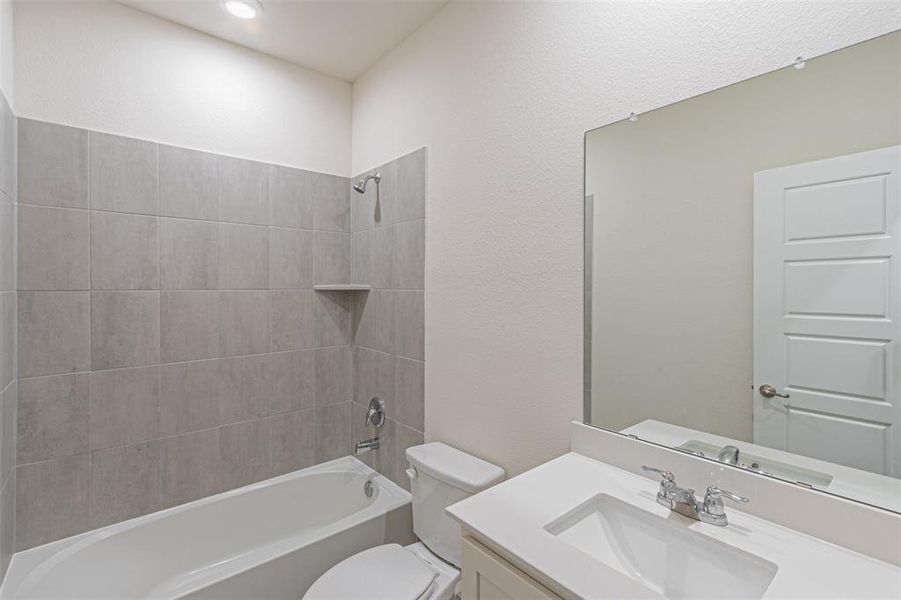 Full bathroom featuring vanity, tiled shower / bath combo, and toilet