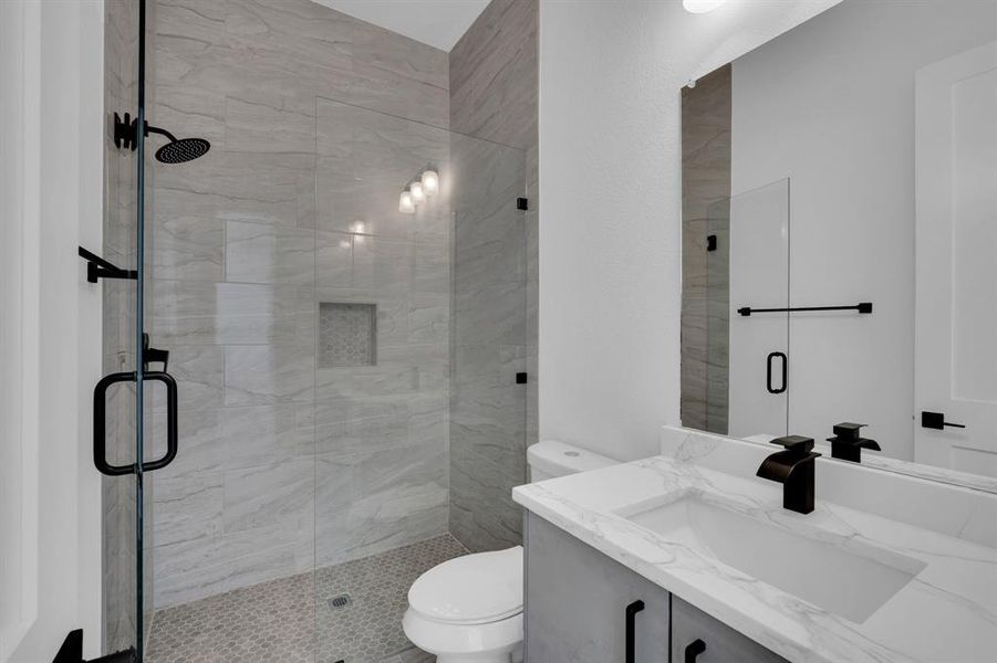 Bathroom featuring toilet, vanity, and a shower with shower door