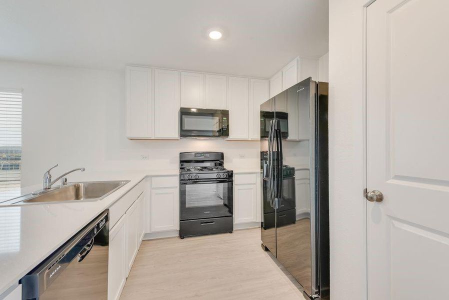 Kitchen featuring white cabinetry, sink, black appliances, and light wood-type flooring